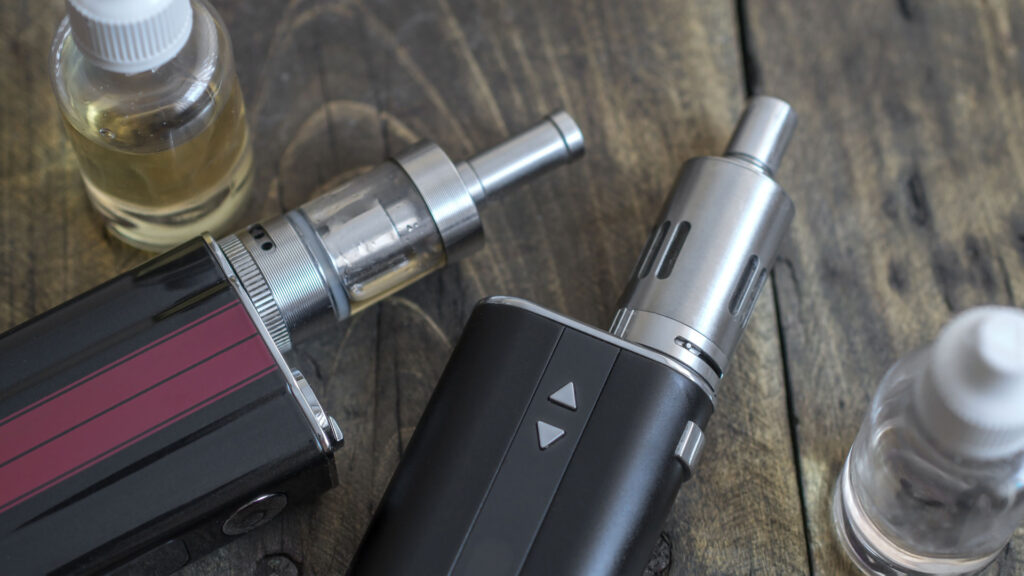 2 vapes placed on table with juice.