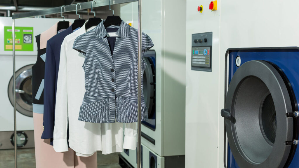 Four Clothes Hanging After Dry Cleaning infront Of Washing Machine.
