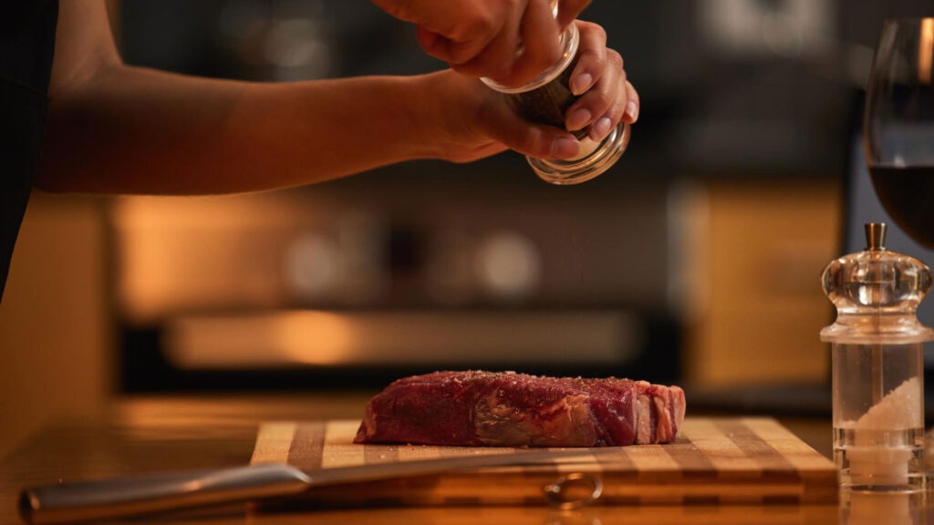 Seasoning a steak.