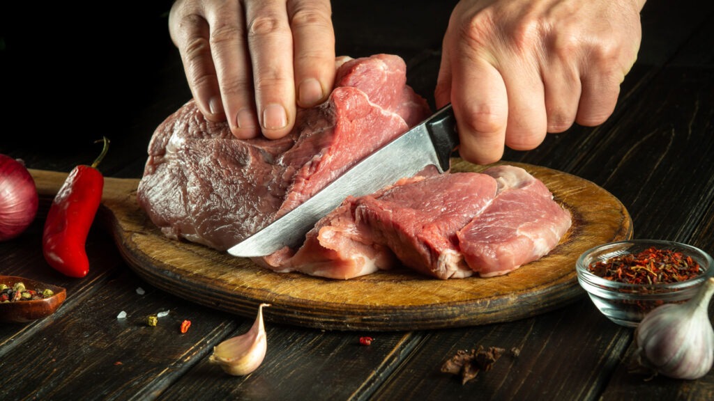 Chef Cutting Beef into pieces.