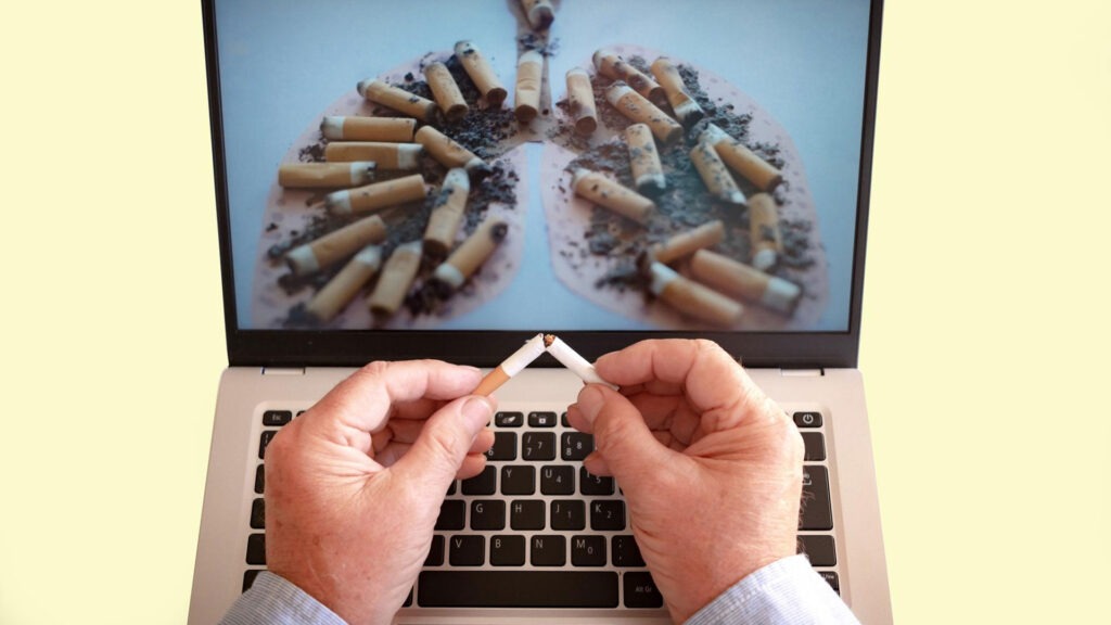 Men breaking cigarette infront of his laptop.